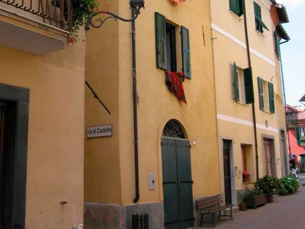 Facciata gialla con persiane verdi della casa indipendente nel centro storico di Calizzano